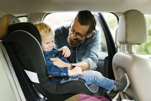 Man putting his son into car seat